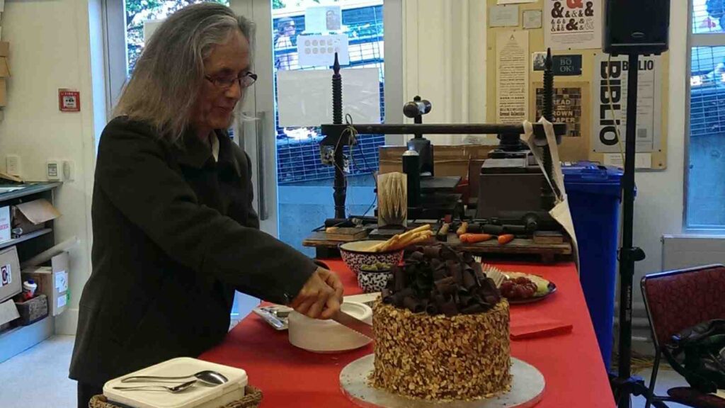 Author Patricia Grace cuts into her birthday cake at Wai-te-ata Press. Image credit: Meredith Paterson